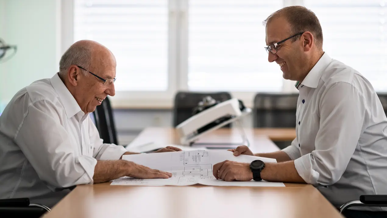 Pfaff Senior und Junior schauen sich gut gelaunt einen Plan an